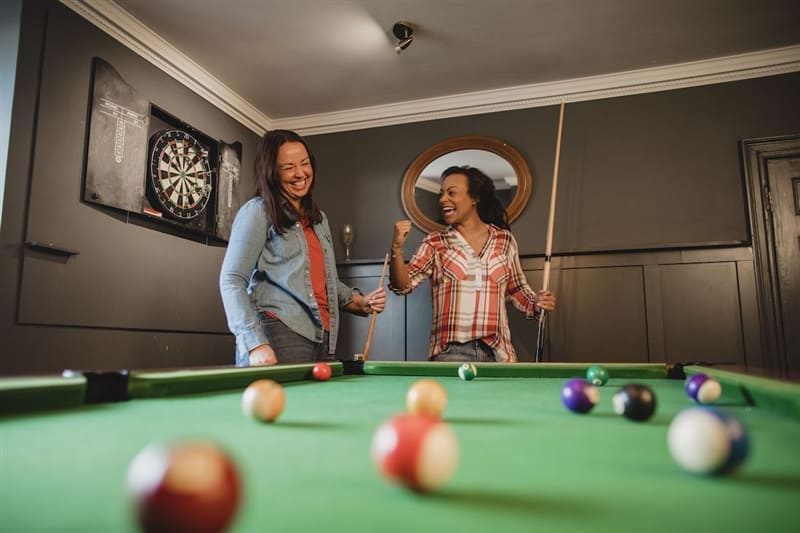 RHB Assets From IGX: Group of friends enjoying a game of billiards in a well-lit room.