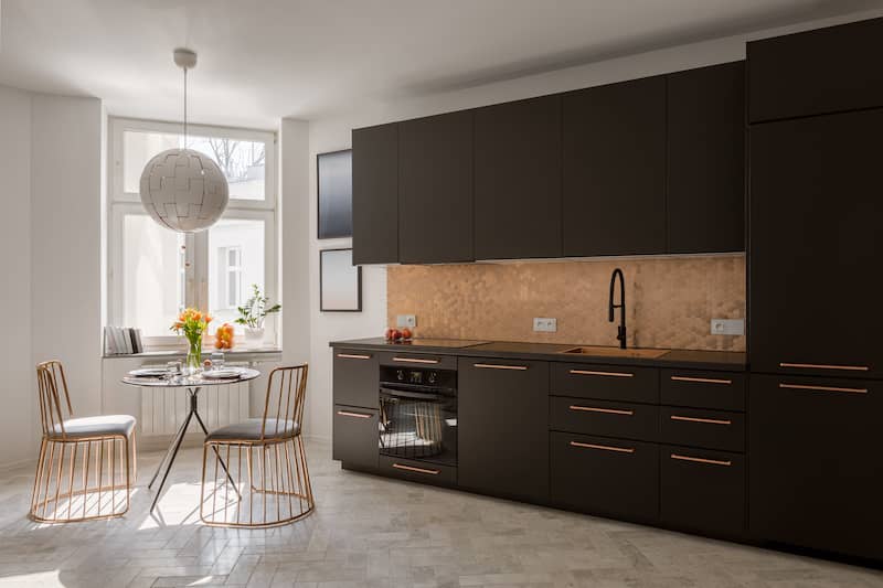 RHB Assets From IGX: Contemporary kitchen featuring a metallic backsplash with geometric patterns, white cabinets, and stainless steel appliances.