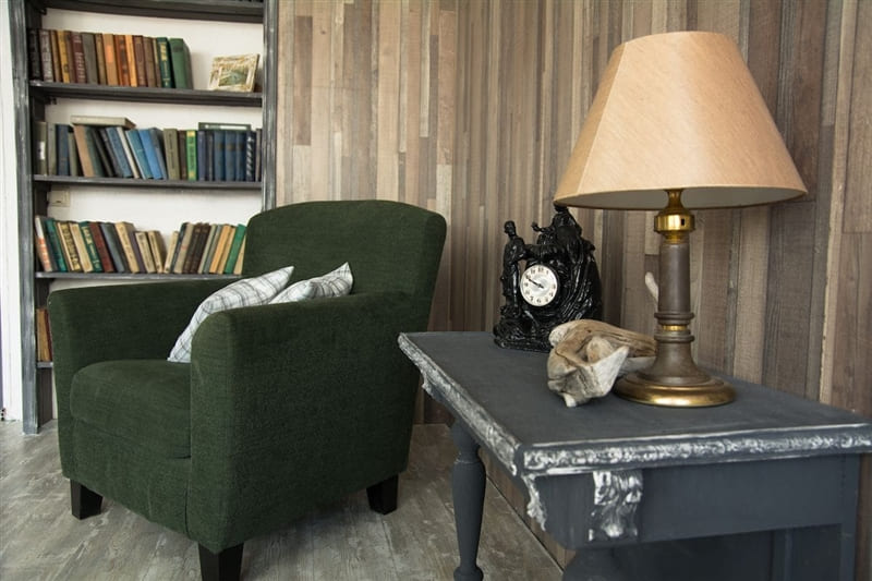 Cozy library with comfy chair surrounded by floor to ceiling bookcases filled with books.