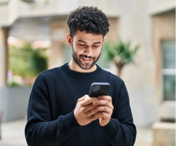 A smiling man looks at the Rocket Mortgage app on his mobile phone.