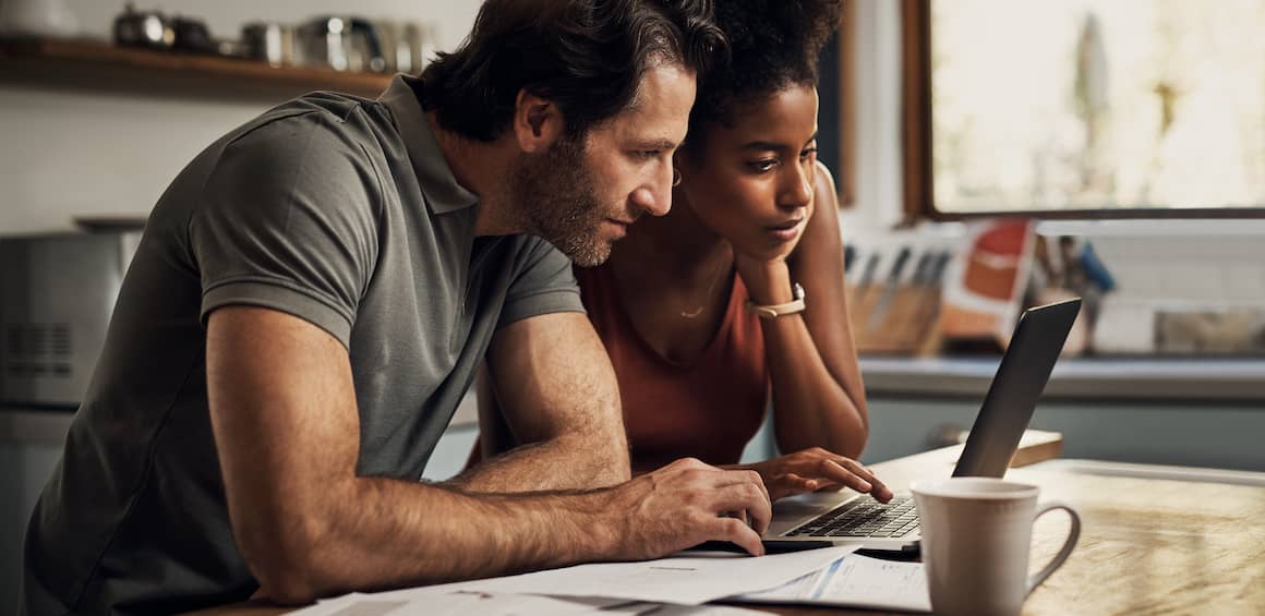 Mixed race couple diligently working while standing on personal finances and budgeting documents.