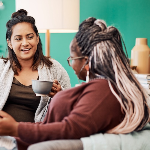 Two women having coffee together in a cozy living room.