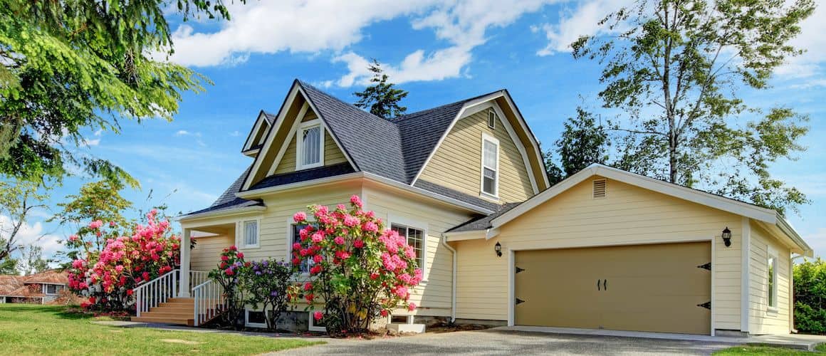 Yellow house with pink flowers in the yard, illustrating residential curb appeal and landscaping.