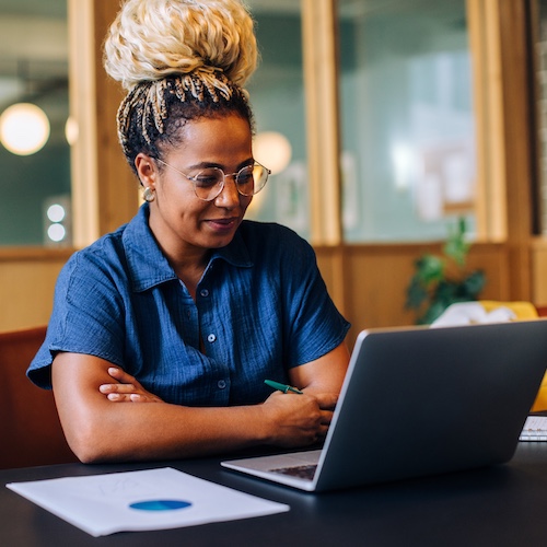 Woman on laptop in office smiling.