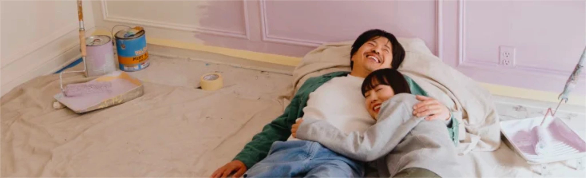 Couple lying on the floor in a freshly painted room, smiling