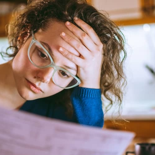 Woman looking over a bill in her kitchen.