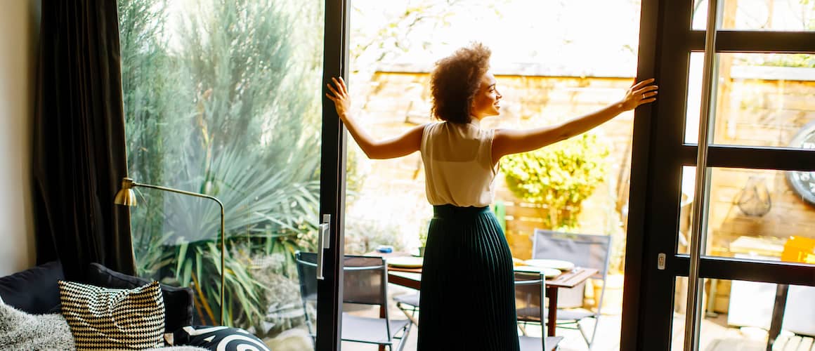 RHB Assets From IGX: Young woman walking onto a home porch with a smile