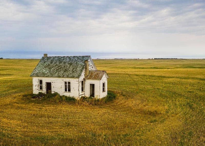 A dilapidated historic home in a field.