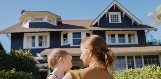 Mother and baby looking at each other in front of their new home.