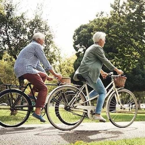 Retired coupld biking through park.