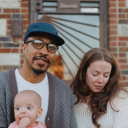 Couple with their young child on lap sitting on porch.