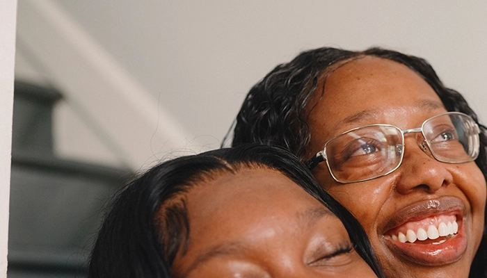 Two women sitting on stairs hugging and crying.