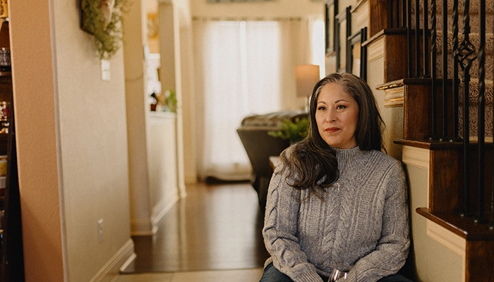 Woman sitting in hallway holding wine glass.
