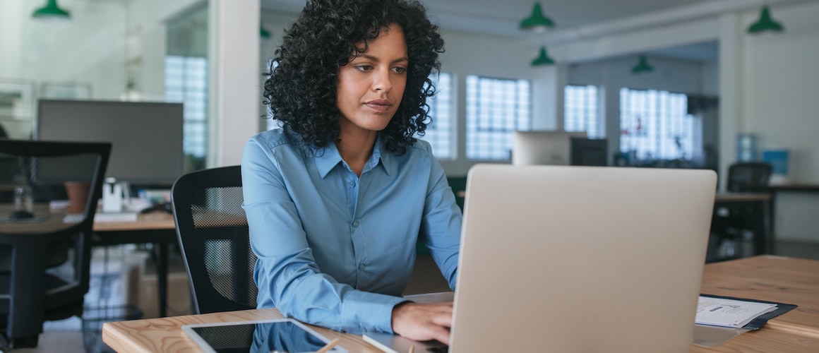 A woman in an office working on a loan application on a laptop.