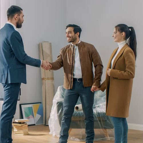 A couple with a real estate agent, engaged in discussion, possibly viewing a property or discussing home options.