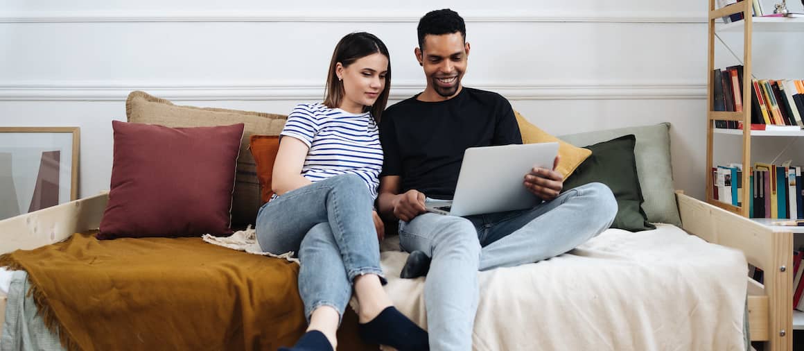 A couple looking at a laptop together, possibly discussing or working on something collaboratively.