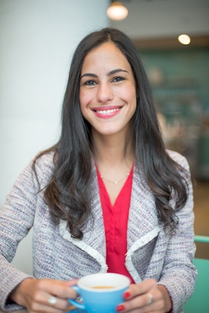 Headshot of Kimberly Hamilton, smiling in a coffee shop, holding a latte. 