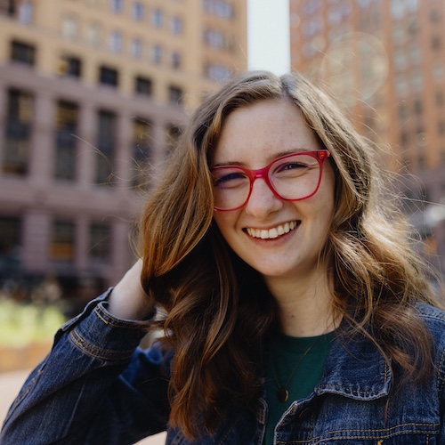 Woman smiling in the city with red glasses.