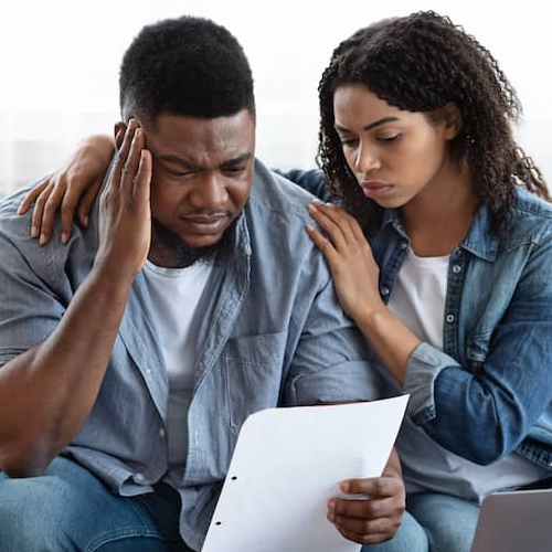 Image indicating a worried couple possibly by taxes or some other information written on the paper.