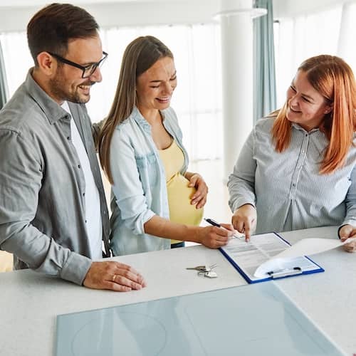 Young couple signing paperwork to buy a new home.