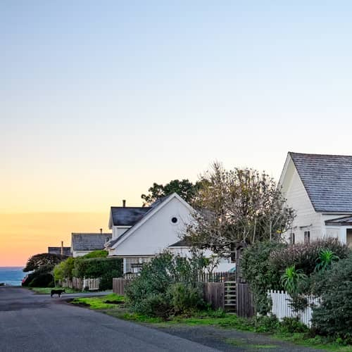 A charming row of houses with a white picket fence, creating a picturesque neighborhood scene.