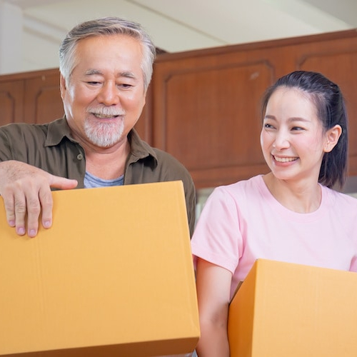 A younger Asian woman moving with a senior father, depicting a family or intergenerational relocation scene.