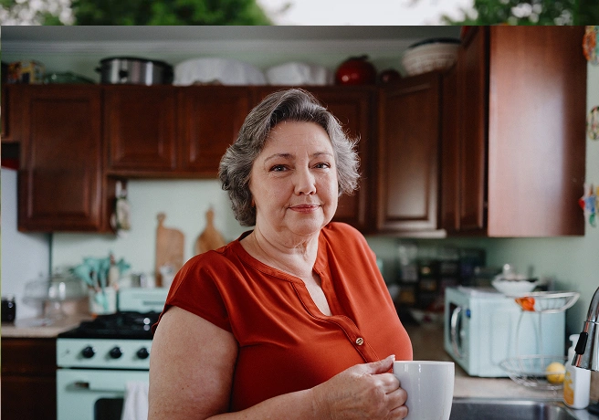 Older woman standing in a kitchen by a countertop