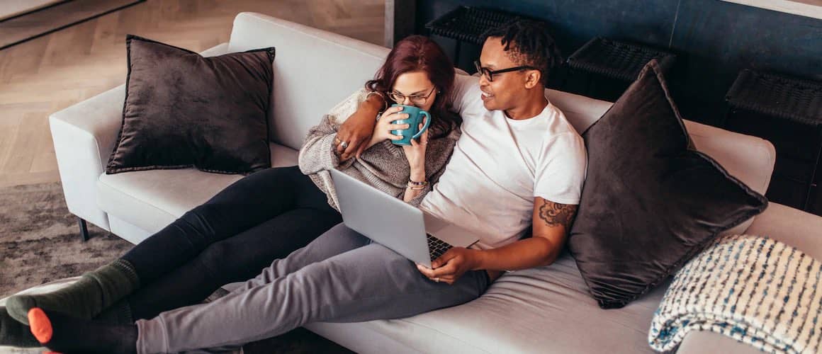 Image of couple relaxing on couch and reviewing credit scores.