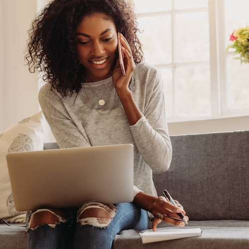 A woman multitasking on a phone call and computer, potentially related to mortgage or real estate inquiries.