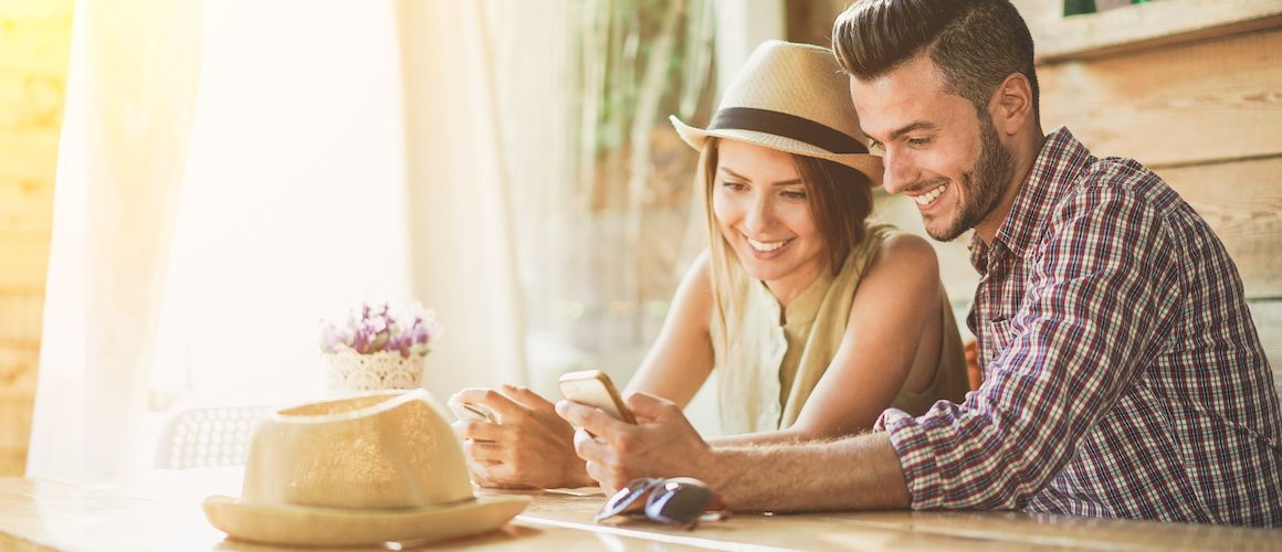 Young couple looking at one phone together.