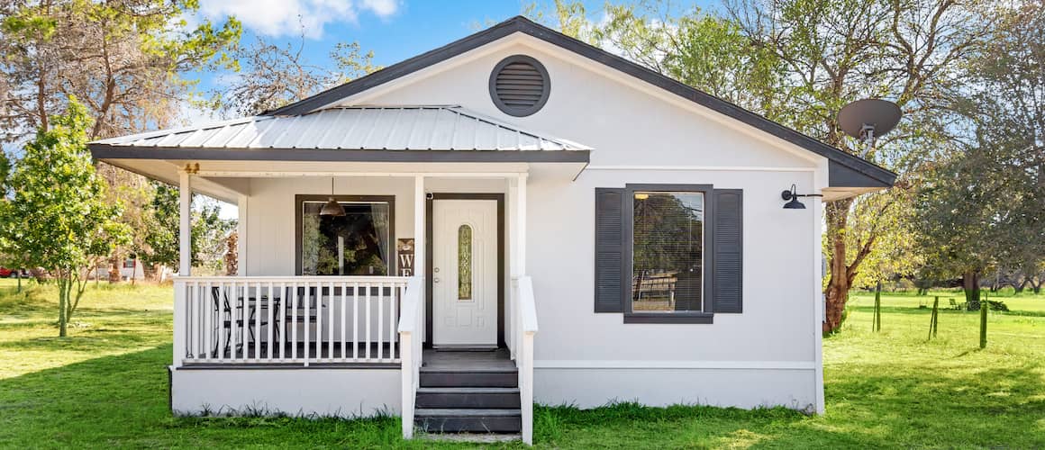 A small white one-story house with a neatly maintained front yard, depicting a cozy residential setting.