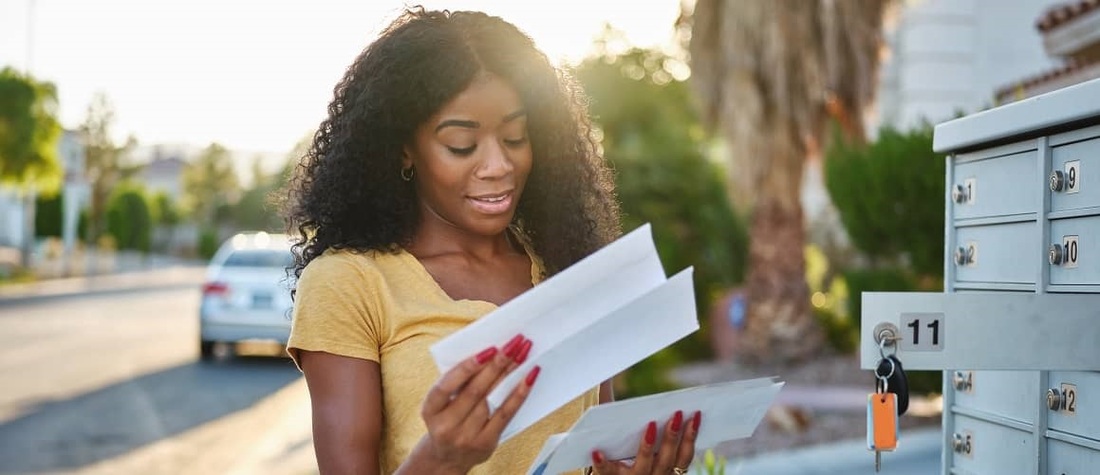 Stock-Woman-Opening-Envelope-In-Front-Of-Mailbox-AdobeStock-270126605-Copy.jpg