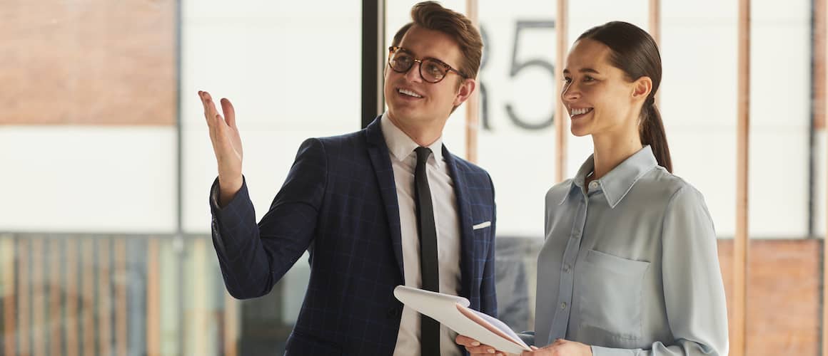 A real estate agent with a client holding a pad of paper, indicating a discussion or consultation.