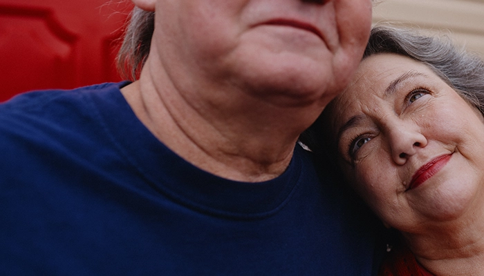 Woman looking lovingly at man while laying head on his shoulder.