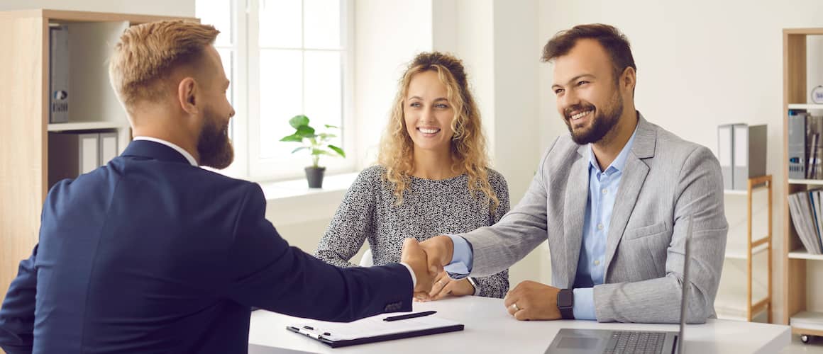 Couple shaking hands with real estate agent when closing on house.