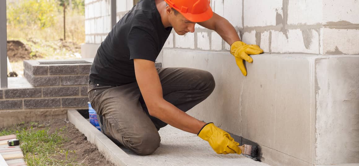 A man working on a home foundation, possibly related to construction or repair work.