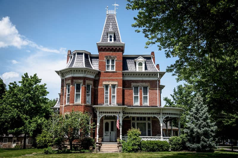 Exterior view of a brick Victorian home with an ornate warp around porch.