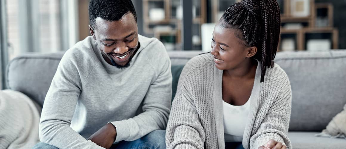 Happy African American couple budgeting together at home.