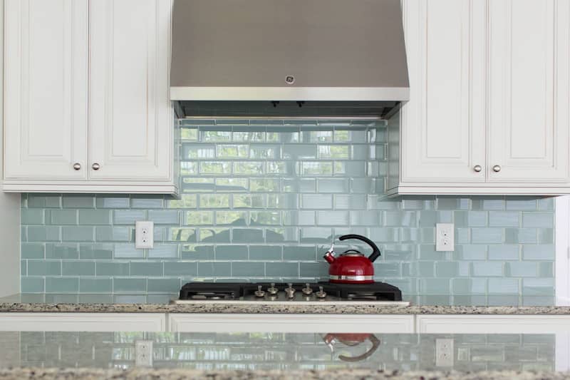 Light blue glass subway tile backsplash behind stovetop.