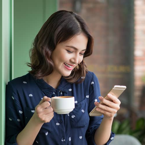 A woman looking at a phone screen, possibly browsing or engaging in real estate-related activities.