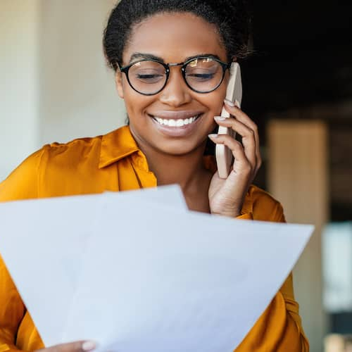 A woman on the phone reviewing a document, potentially related to financial or property matters.