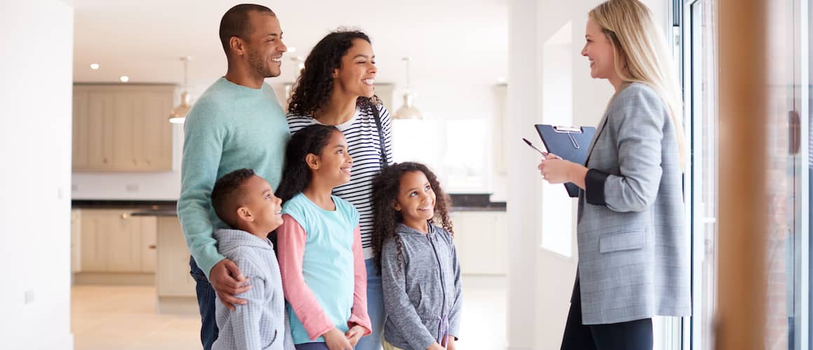 Family of five in a home with a realtor.