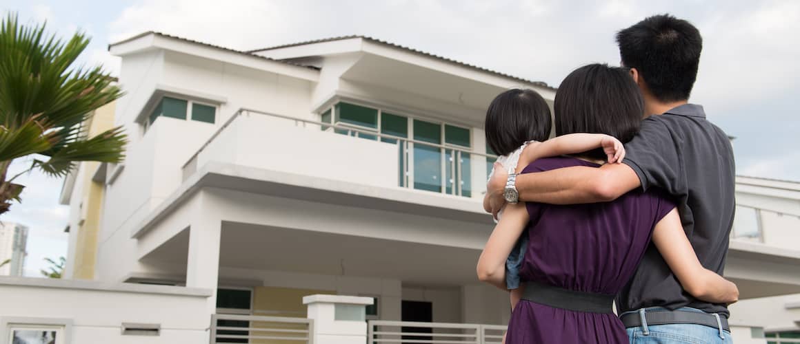 Couple with baby standing in front of their new modern-style house.