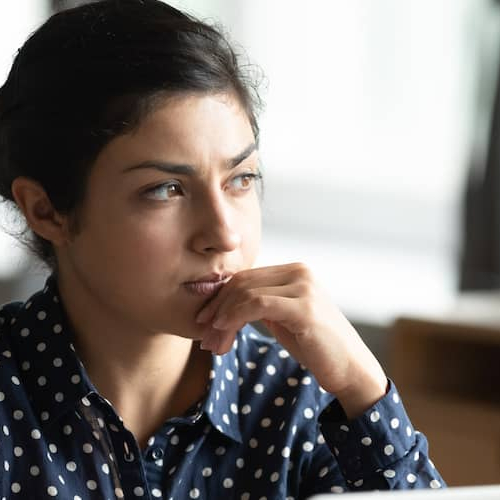 Image of a pensive woman, possibly considering real estate or financial decisions.