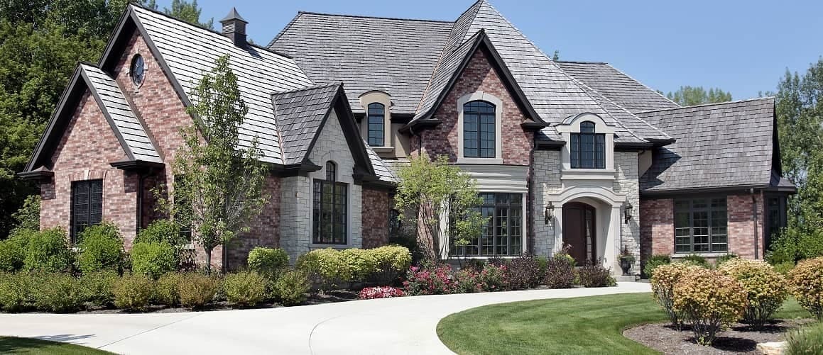 Large white two story house with porch atop a vast green lawn.