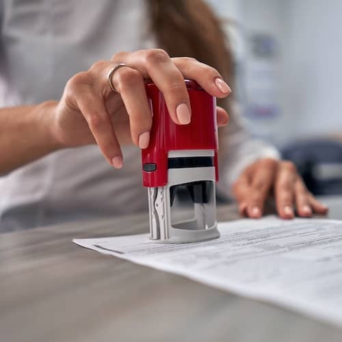 An individual stamping a document with what appears to be a notary stamp.
