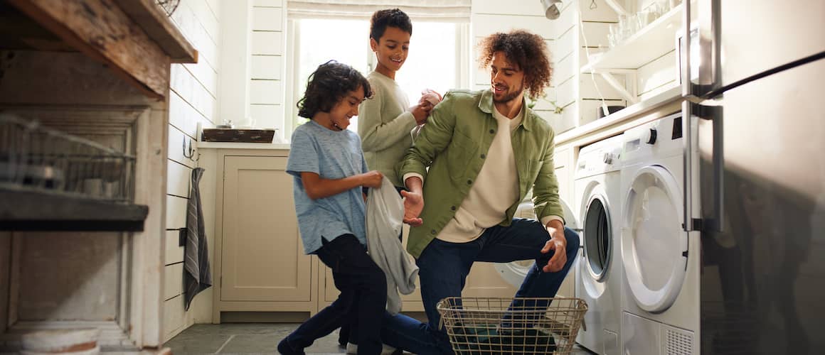 A father doing laundry with his sons, representing family life or household activities.