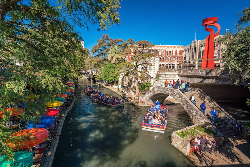 RHB Assets From IGX: San Antonio River Walk with vibrant buildings and waterfront walkways.