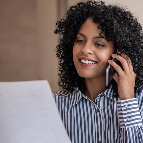 Woman on phone looking over financial documents.