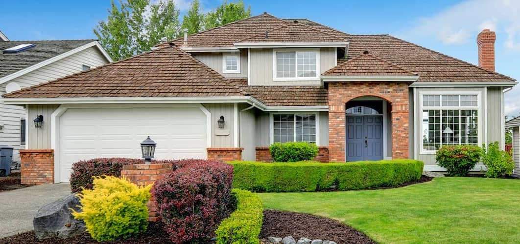 A house with green grass and bushes, indicating a well-maintained property with landscaping.